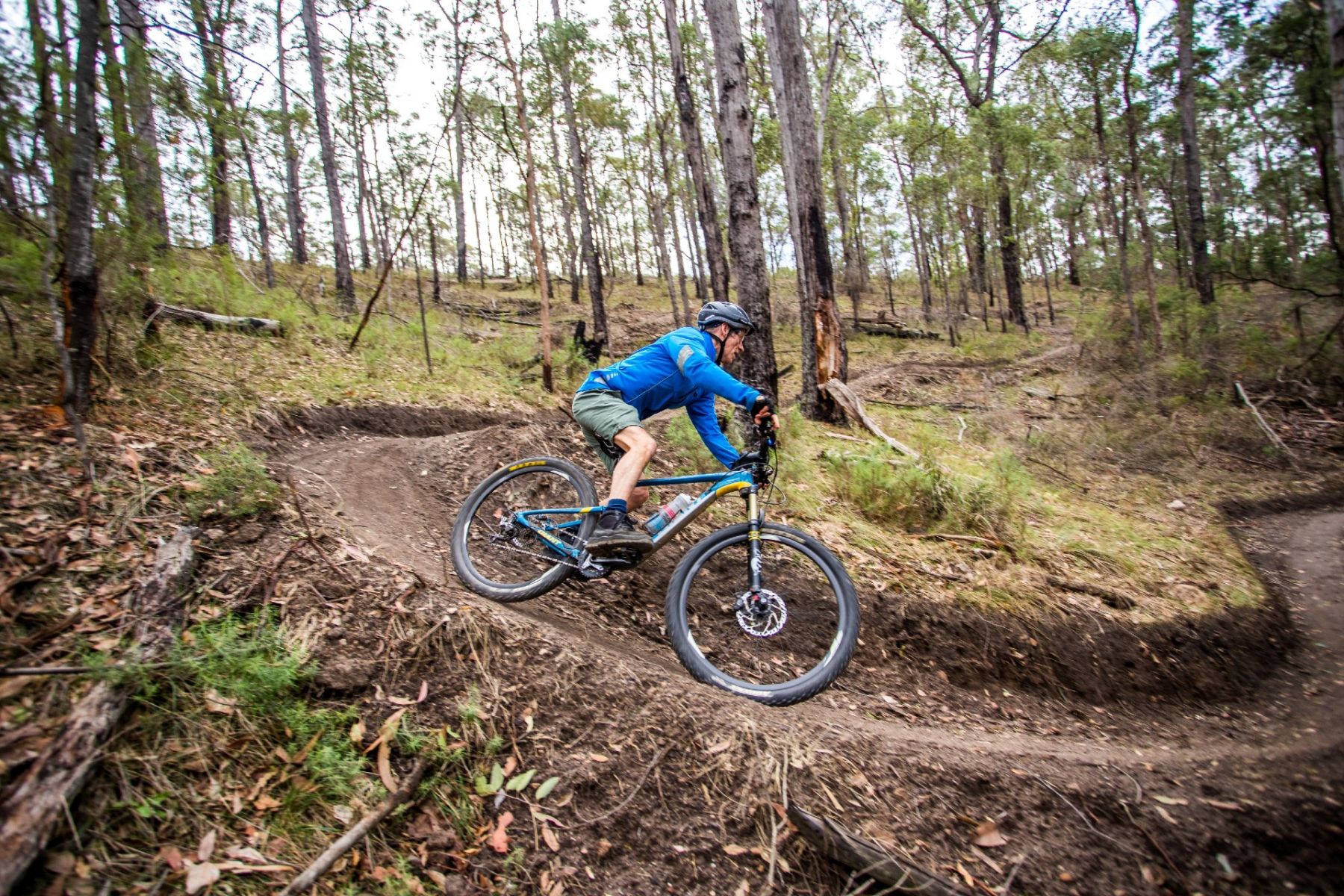 A man on a mountain bike taking a steep corner on a dirt track
