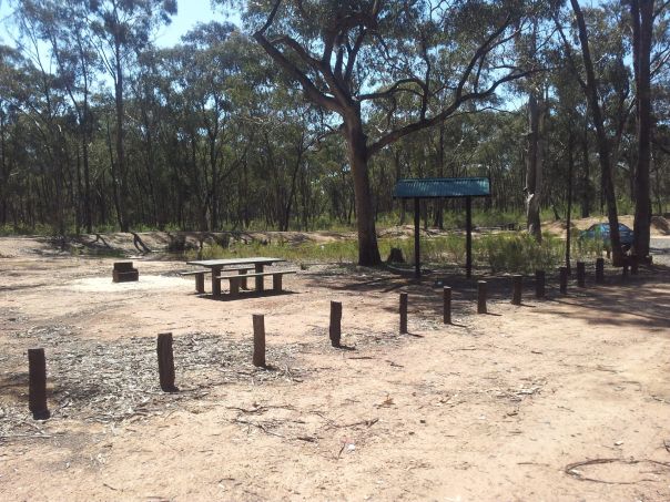 A basic campground with a picnic table and shelter