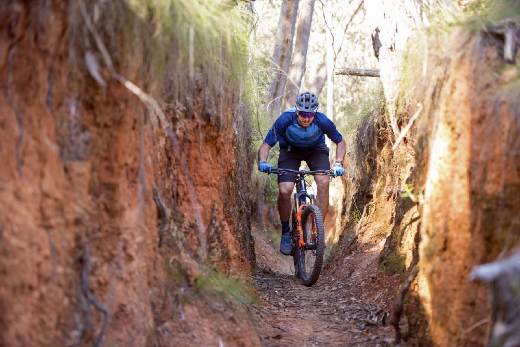 Person riding mountain bike through narrow gully