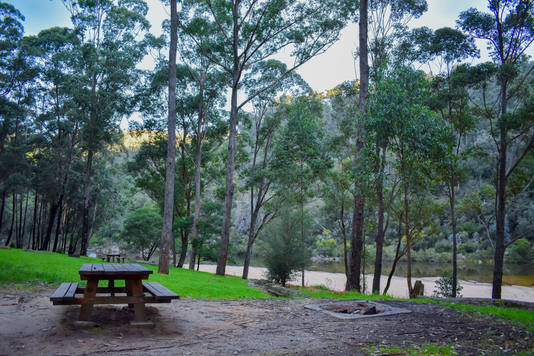 A wooden picnic table overlooking a river in the forest