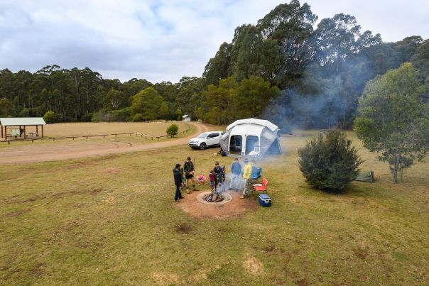 A group of friends set up camp in an open and grassy area