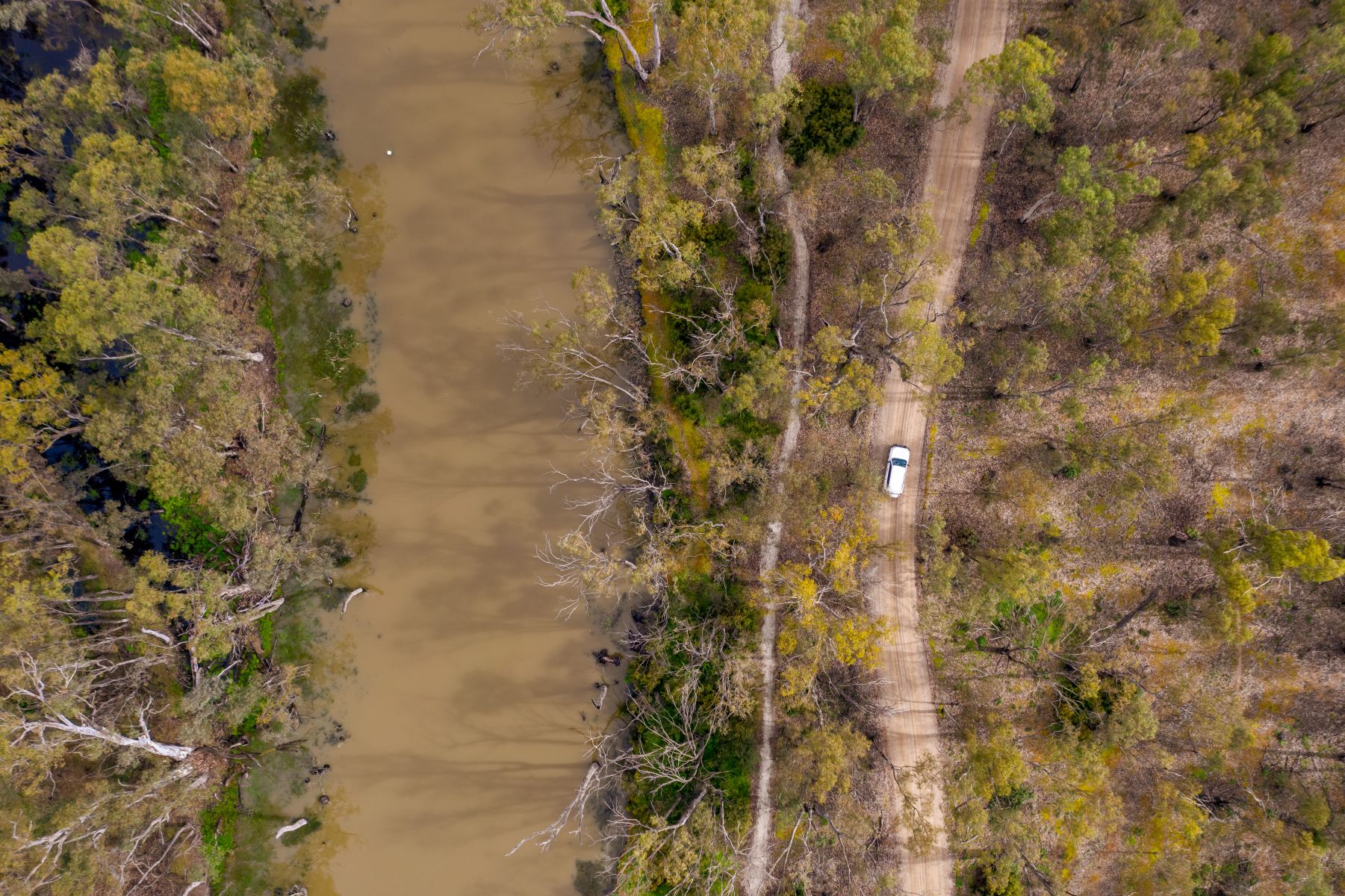 An aerial view of a river running alongside a dirt track
