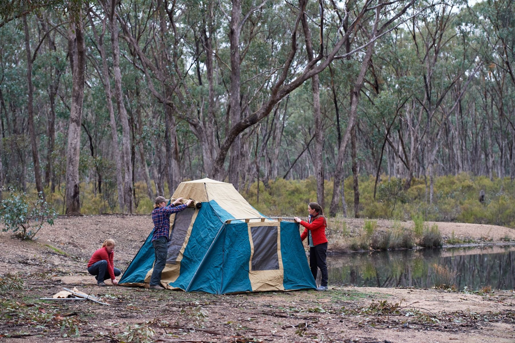 A group of people set up a tent next to a lake. 