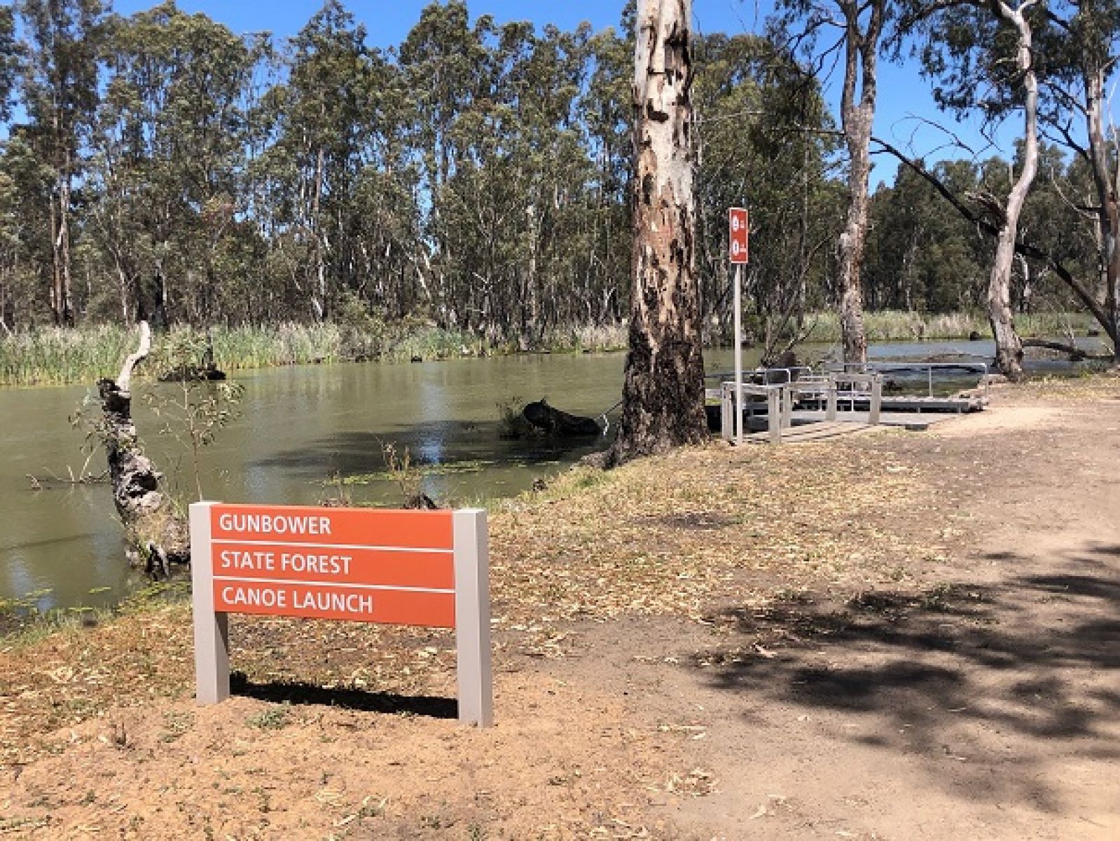 A sign next to Gunbower Creek that reads Gunbower State Forest Canoe Launcher