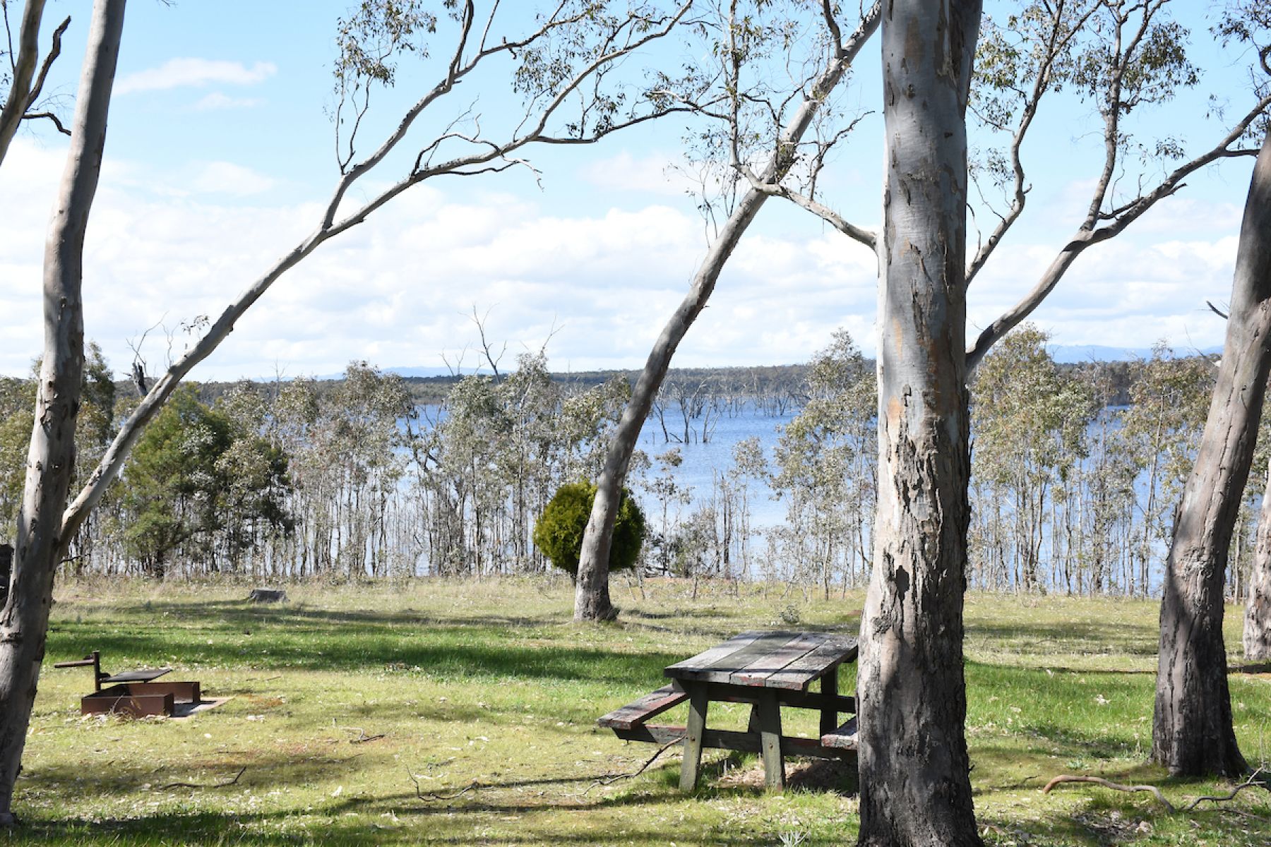 A picnic table on grass close to a reservoir