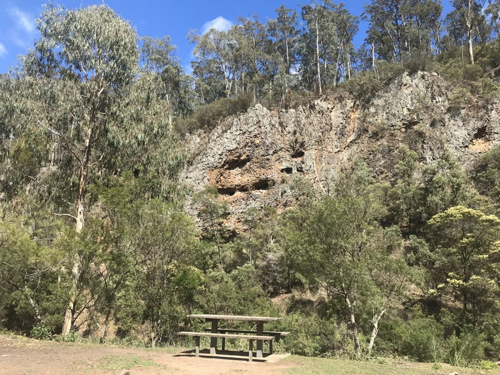 A picnic table with a view towards rocky sliffs surrounded by forest