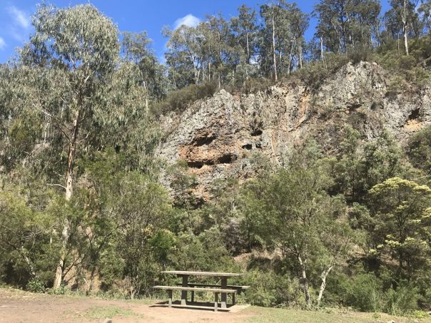 A picnic table with a view towards rocky sliffs surrounded by forest