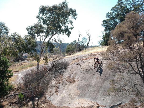 A bike rider about to descend on a steeply sloped rock face