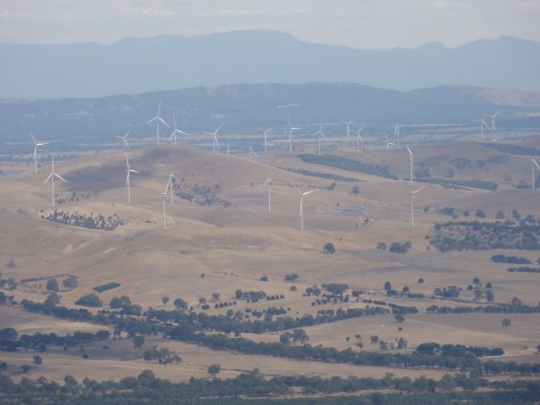 A view from a height of a wind farm and hills in the background