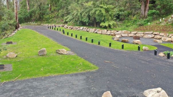 Gravel road and walking track connecting communal fire pit in grassed campground