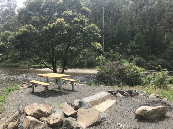 A picnic table by the river at Bruntons Bridge Campground