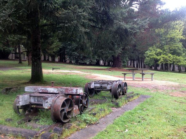 Old remnants of a saw mill on grass with a picnic table and trees