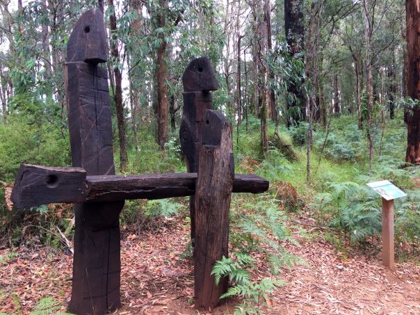 A piece of environmental art made from wood stands in a forest