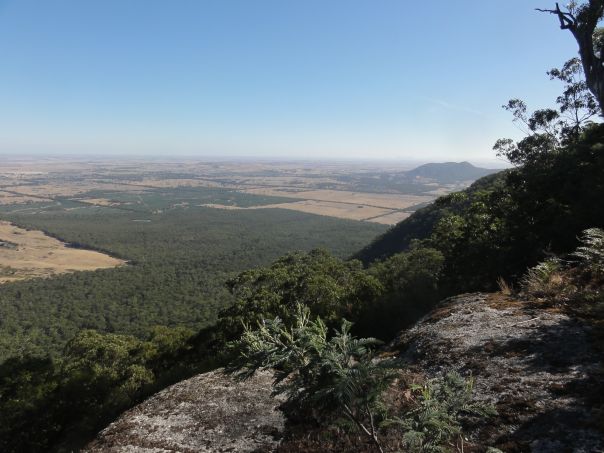 A view from a height of plains below and a hill in the distance