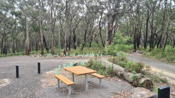 A gravelled area of a campground with a picnic table
