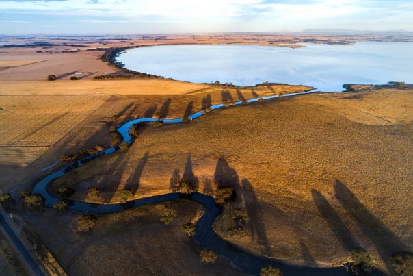 An aerial view of a river connecting to a large blue lake