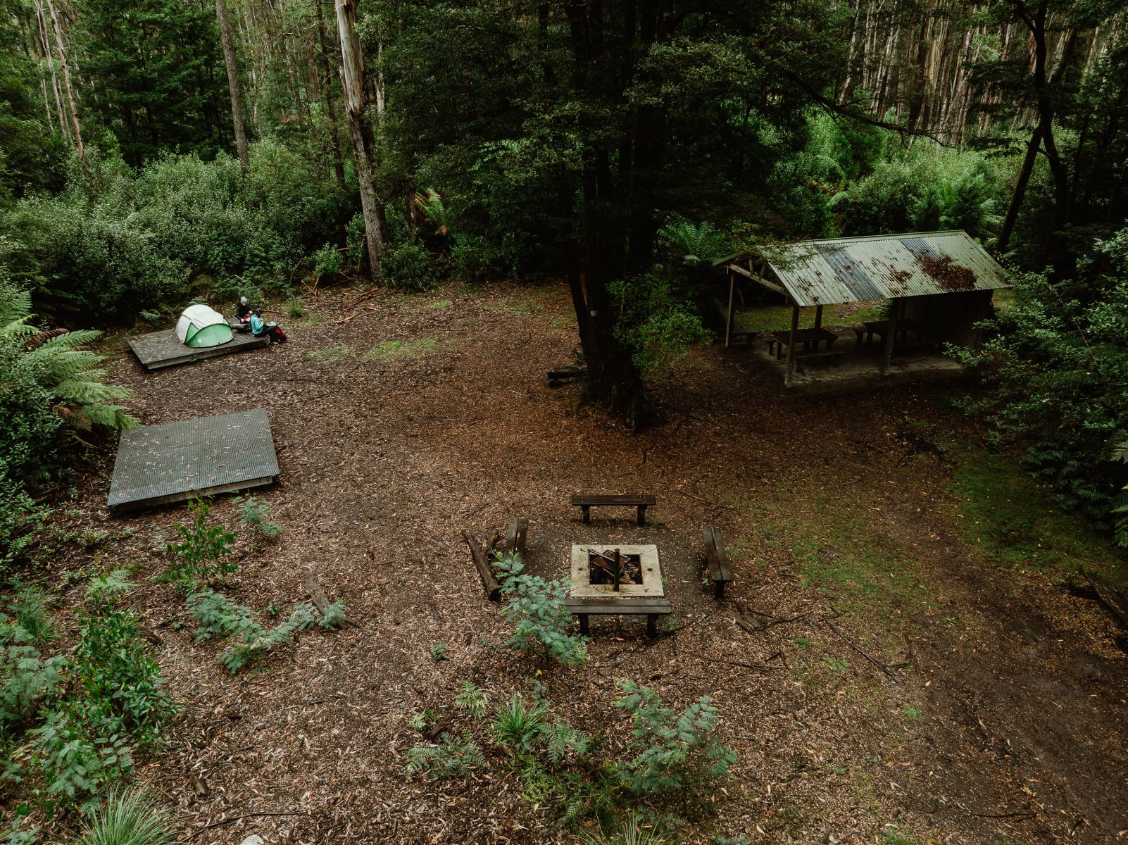 Aerial view of tent platforms and picnic shelter surrounded by forest