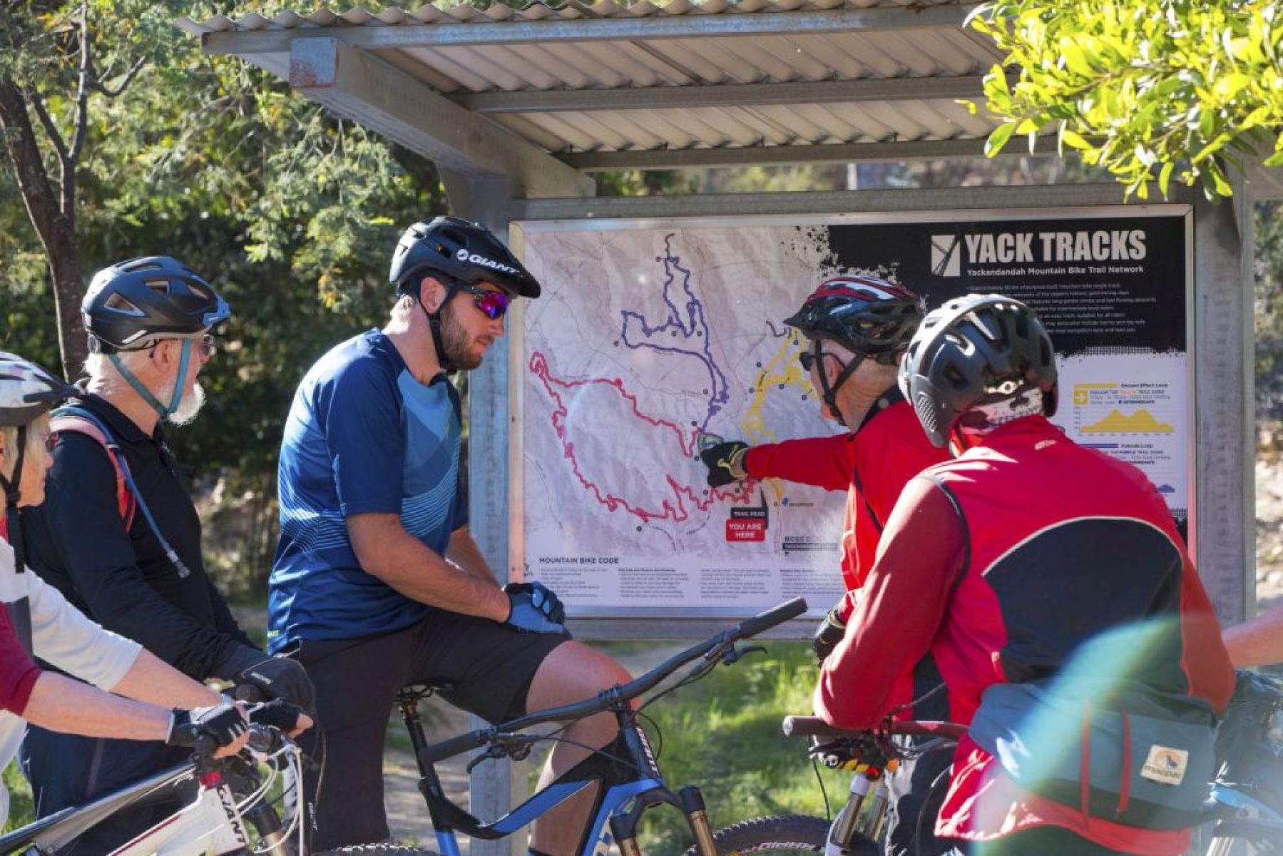 4 people on bikes looking at a sign