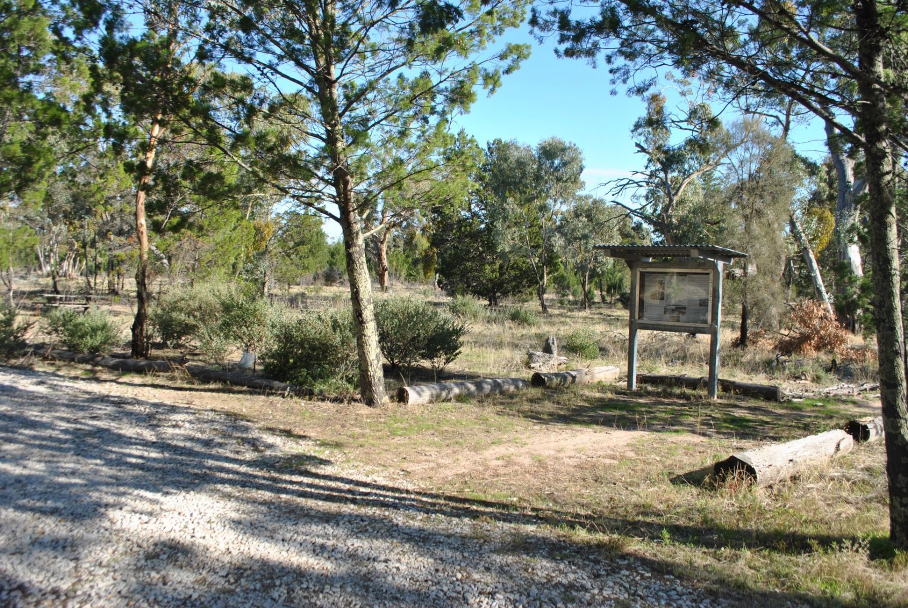 A gravel area and grass with an information signboard