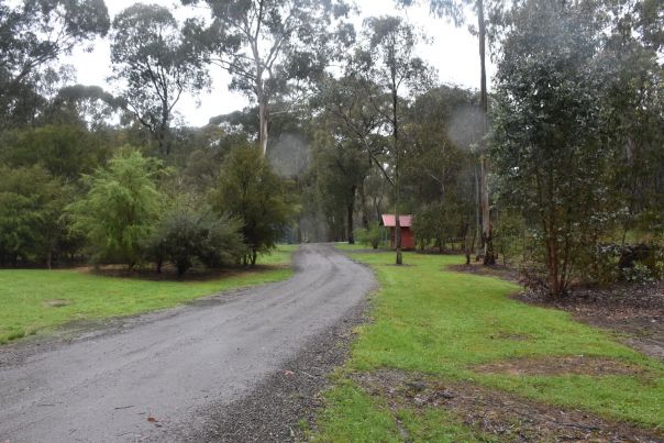 The gravel entrance road into the campground that shows the spacious grassing camping area