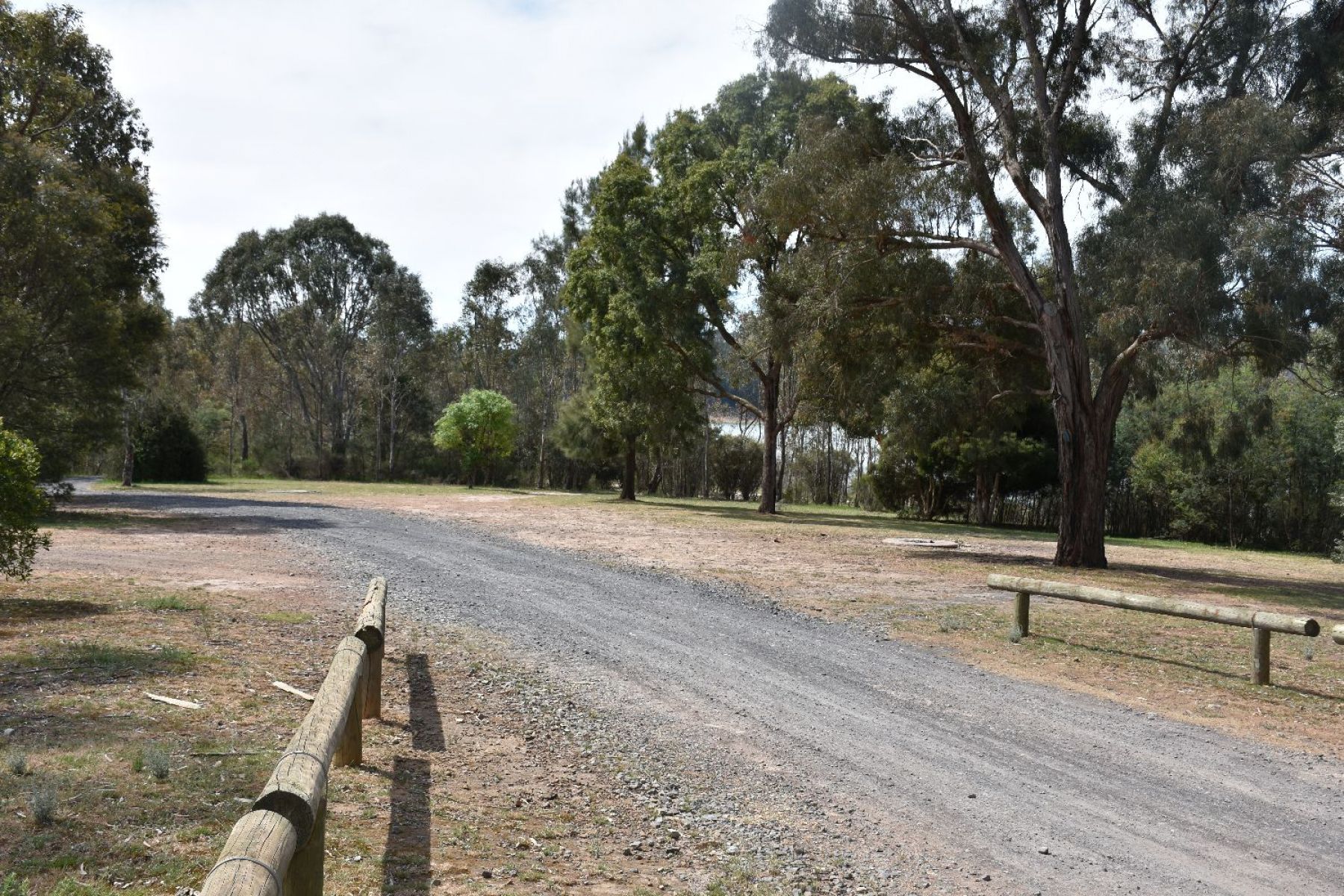 Gravel road entrance to the site, with big open camping spaces and the shoreline in site