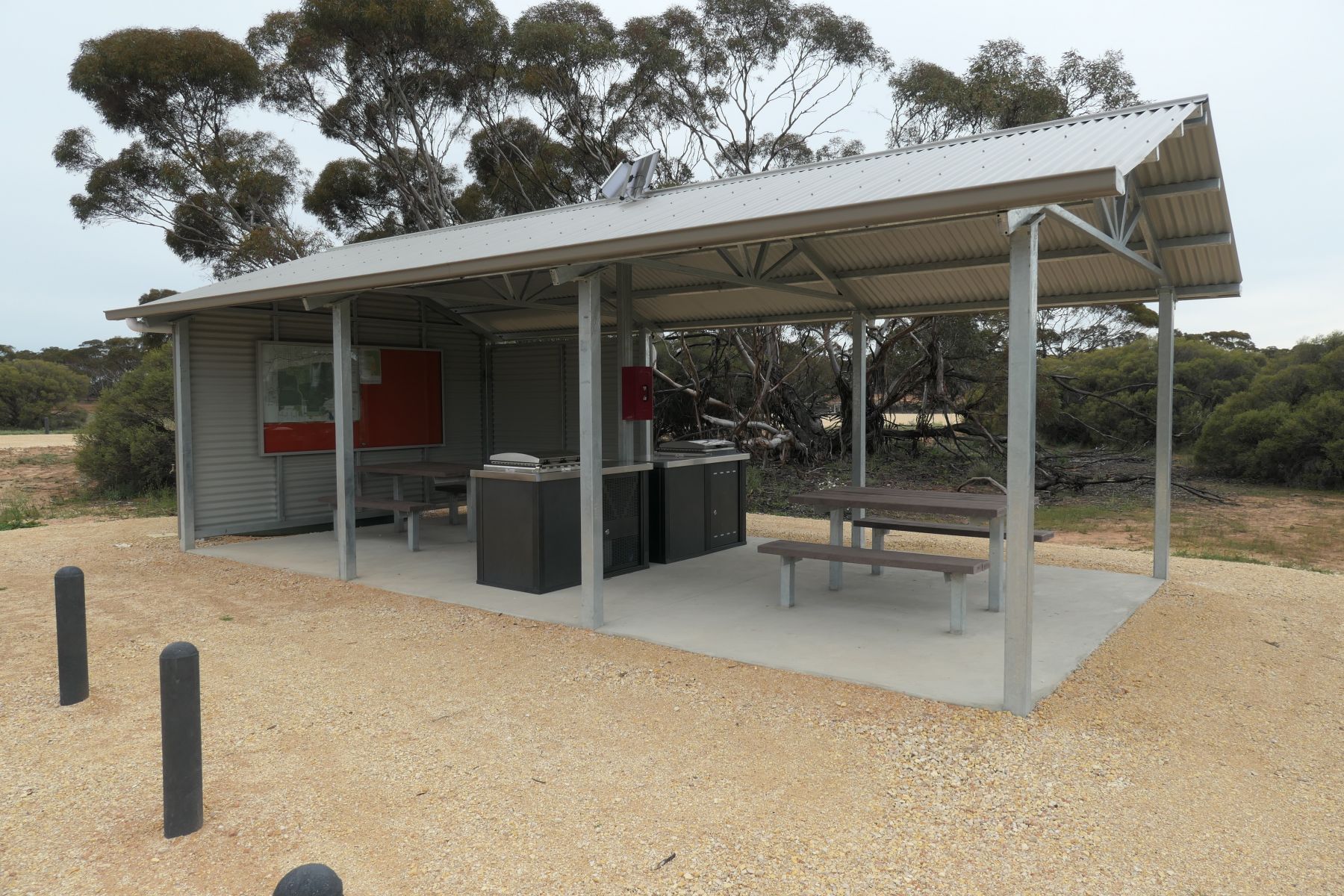 A metal picnic shelter with wooden tables.