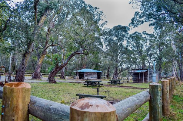 Fency in foreground with hut and shelter surrounded by grass