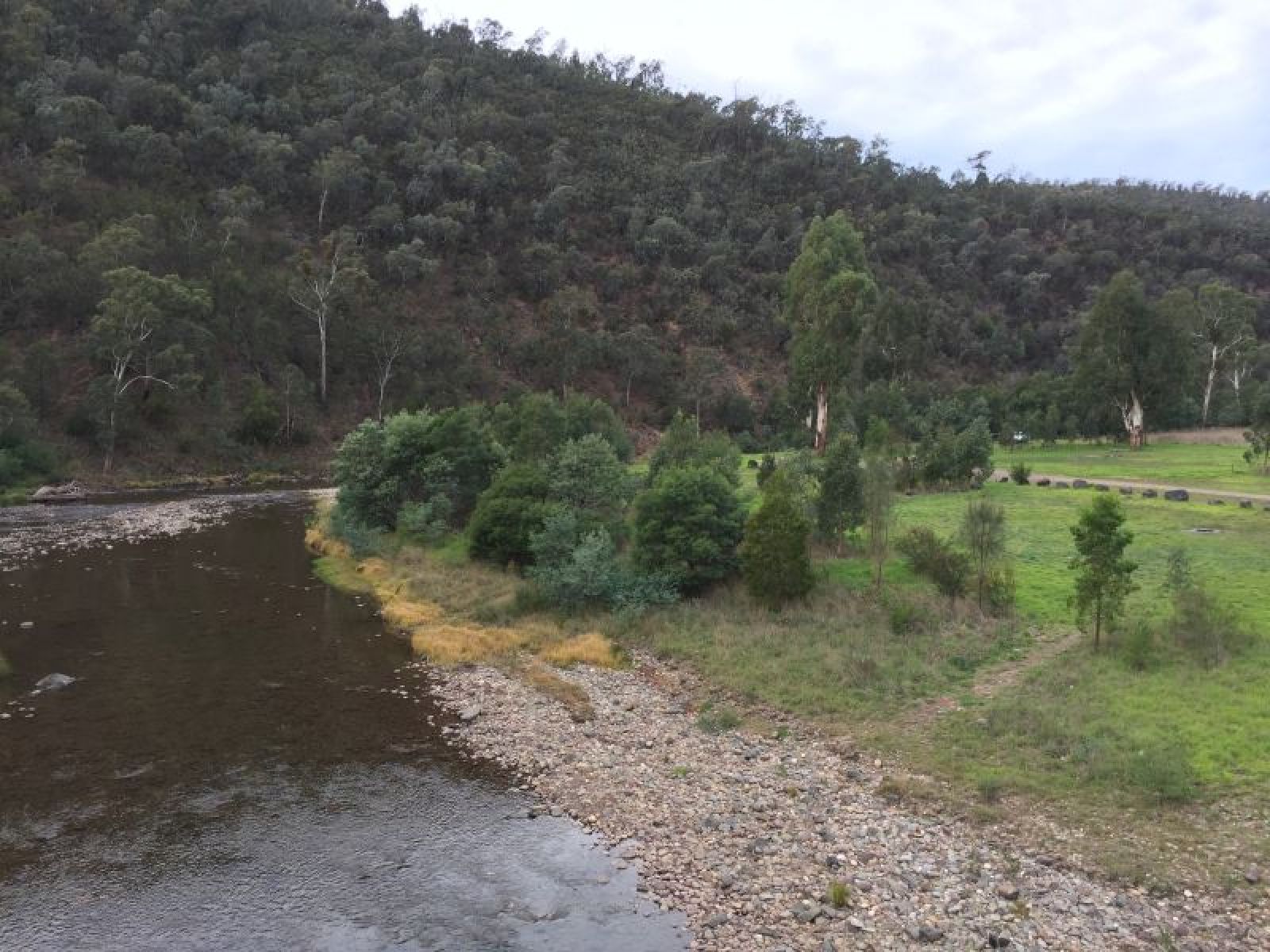 River running past a grass campground