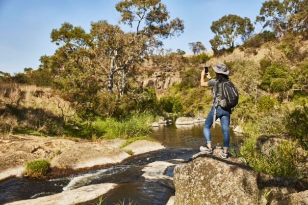 Woman standing on a rock look at a creek