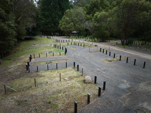A gravel road in a flat camping area. Single carparks come off the road for people to park their cars while camping. 