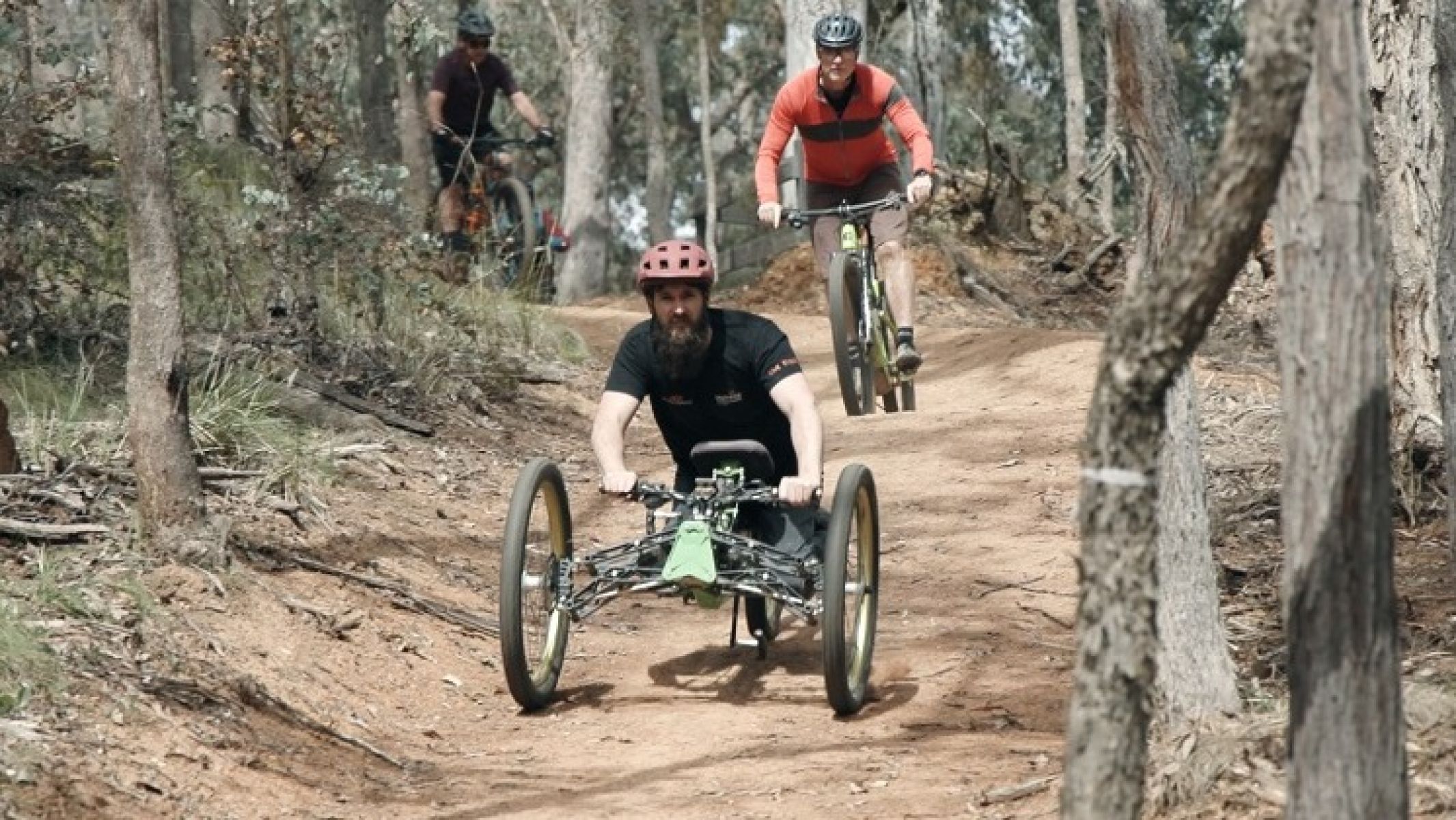 Person riding adaptive mountain bike surrounded by forest
