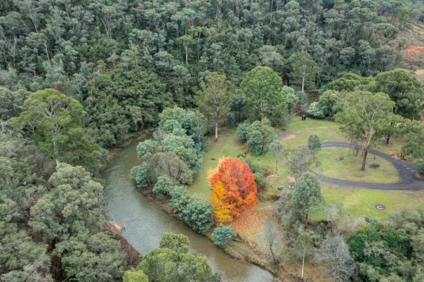 An aerial image of a campground in the forest with a river running through. 