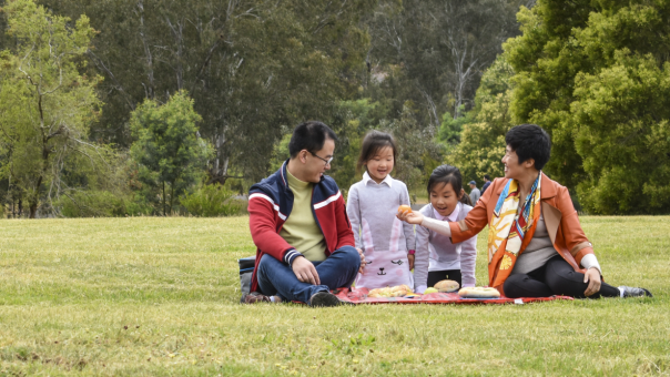 A family enjoys a picnic in an open grassy space