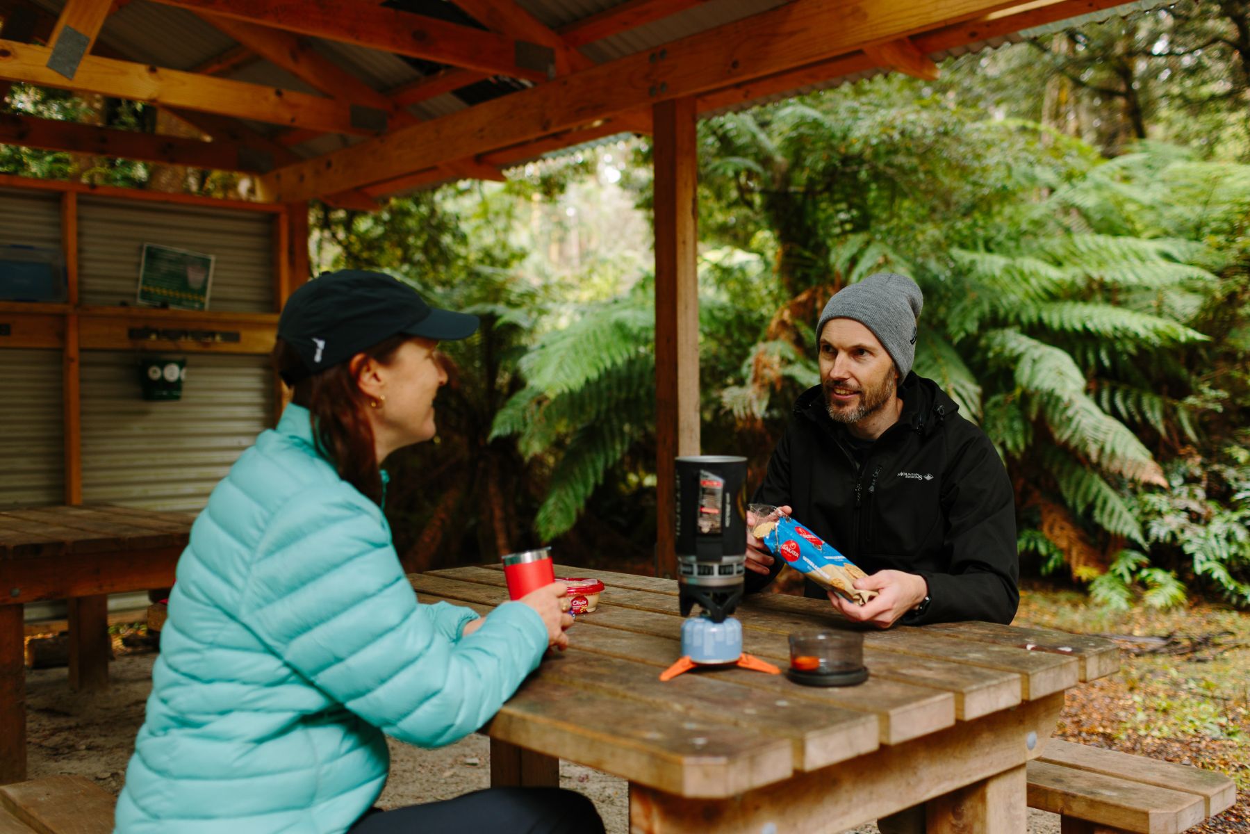 Two people sitting under shelter in the lush forest