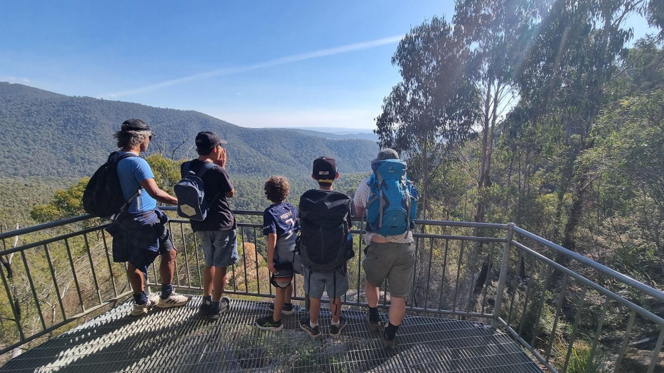 People on a lookout platform overlooking forested mountains