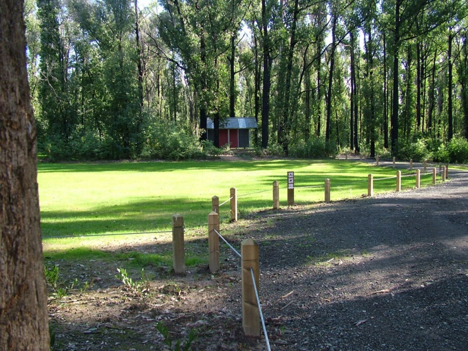 A gravel road next to a grassy campground