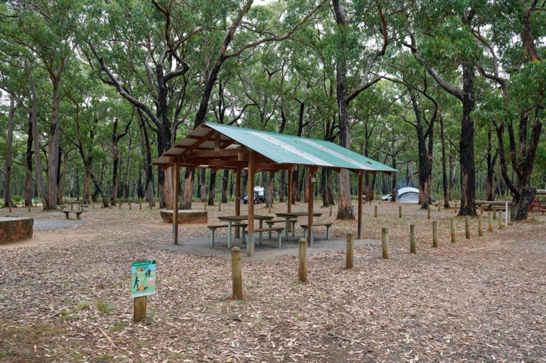 A picnic shelter in a campground surrounded by large trees