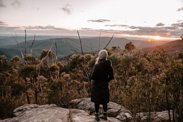 Person standing in forest looking out over mountain views