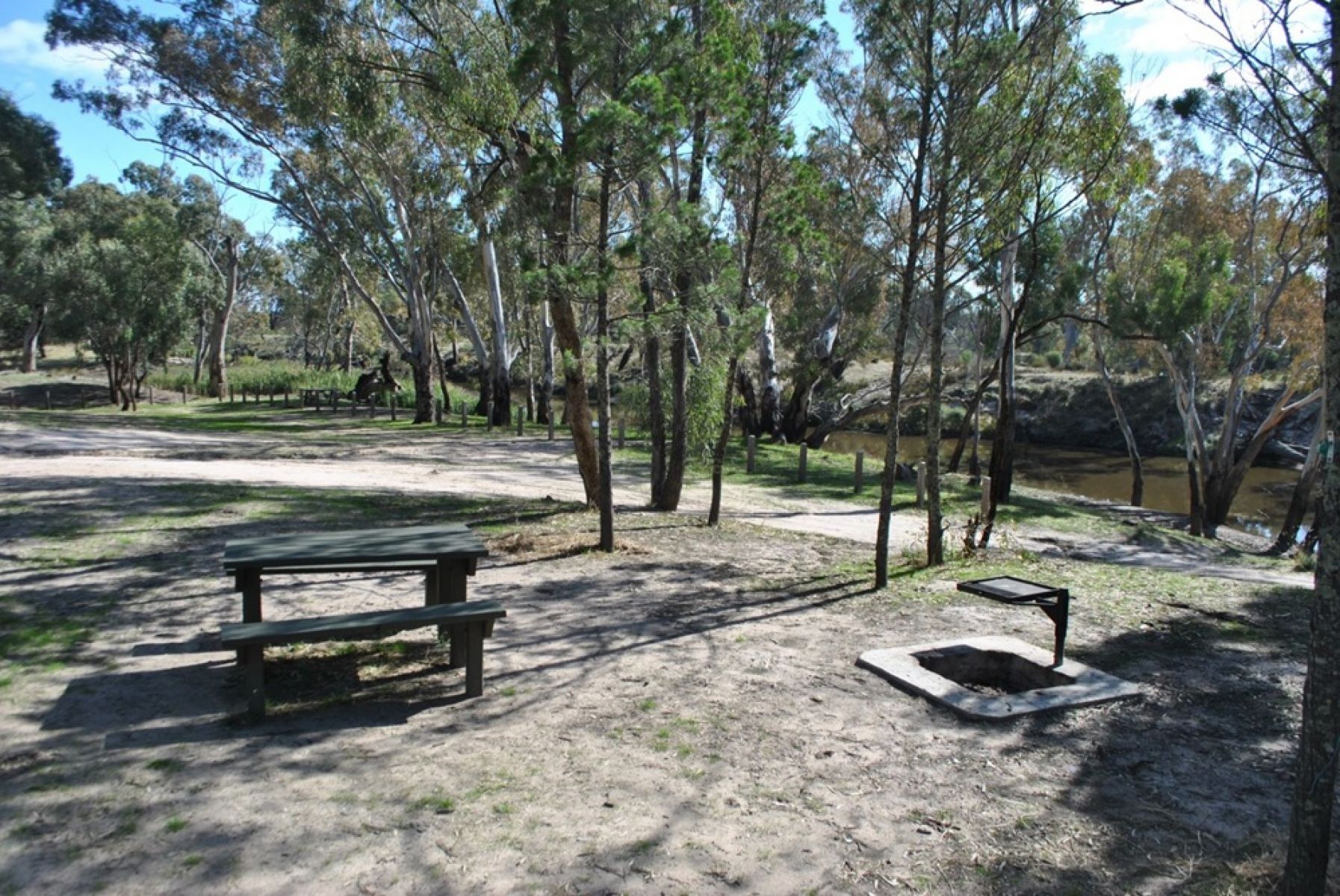 A campsite beside the river featuring a picnic table and campfire