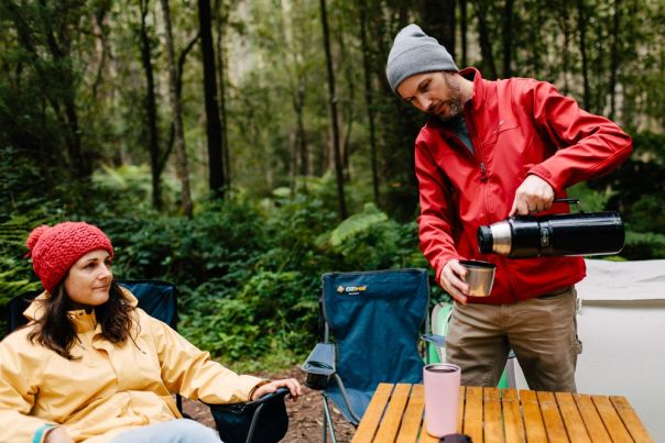 Two people at a table having a drink in the forest