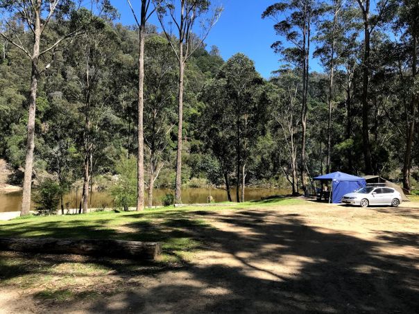 A car and a tent by a river. 