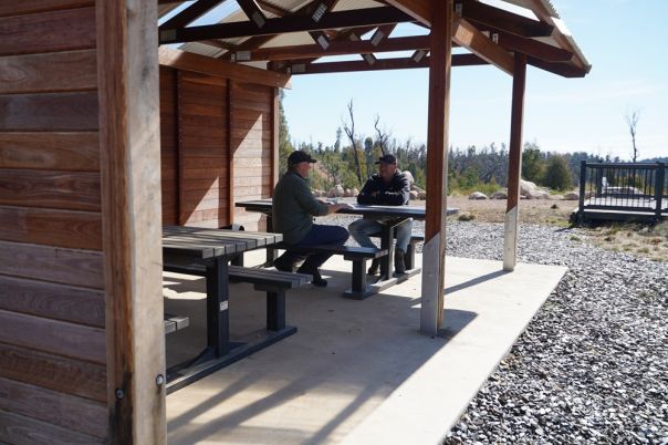 Two people at a picnic table under a shelter