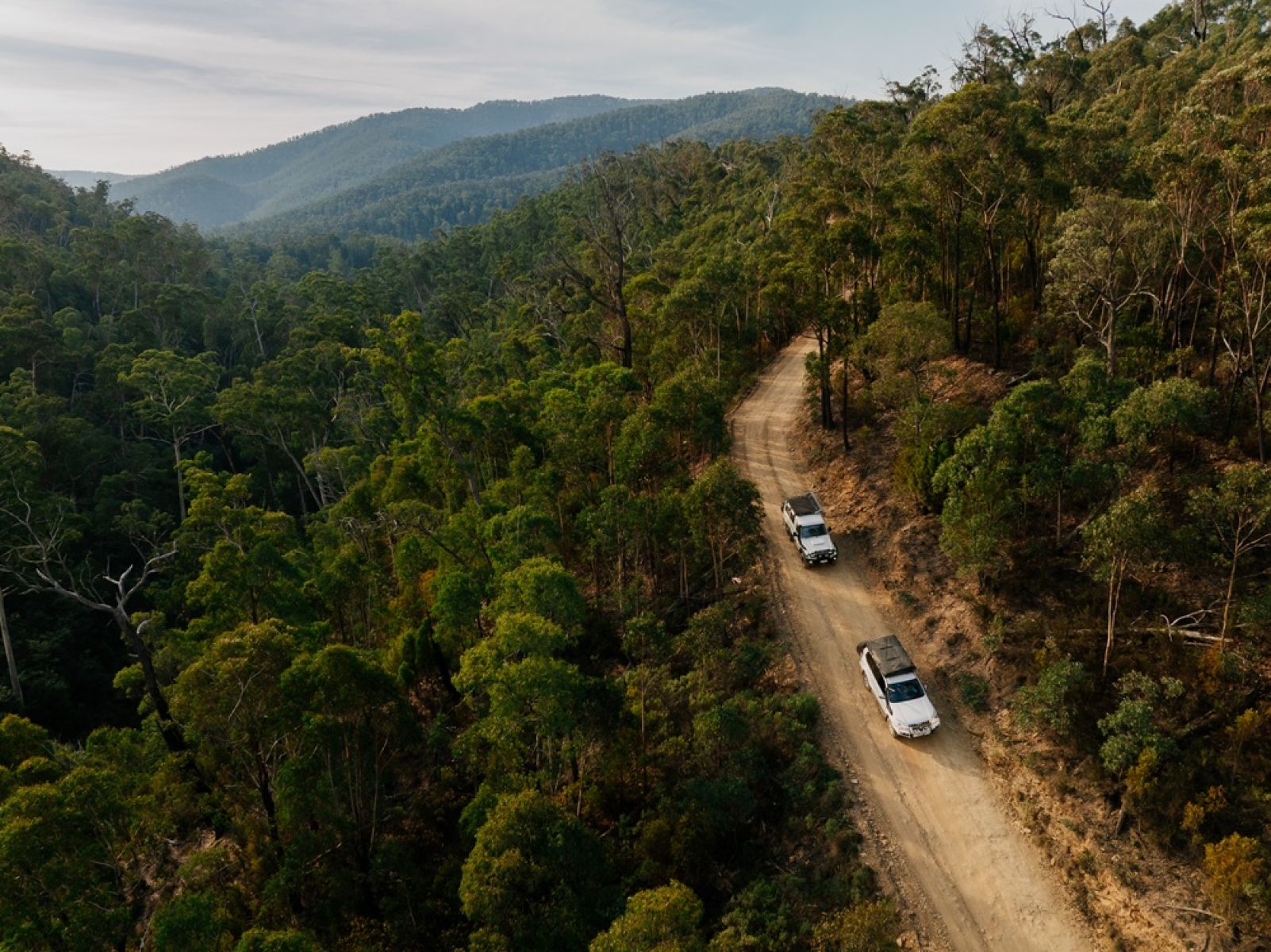 Two 4WD vehicles on a gravel road in the mountains