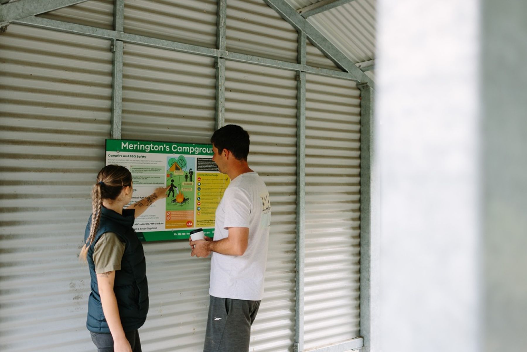 Two people reading a sign in a picnic shelter