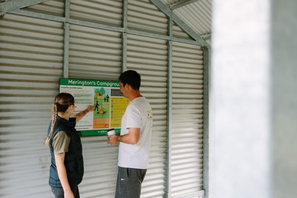 Two people reading a sign in a picnic shelter