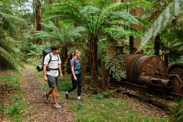 Two people with backpacks in front of old equipment