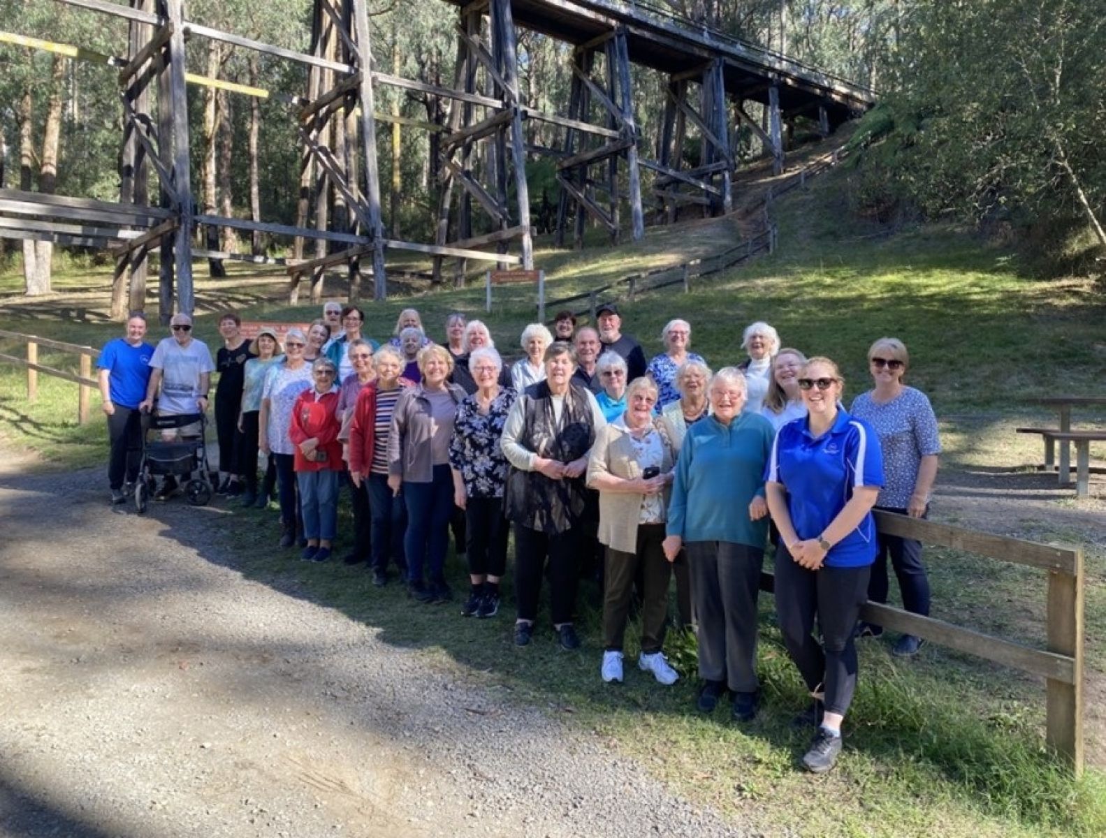 A group of people standing in front of a wooden trestle bridge.