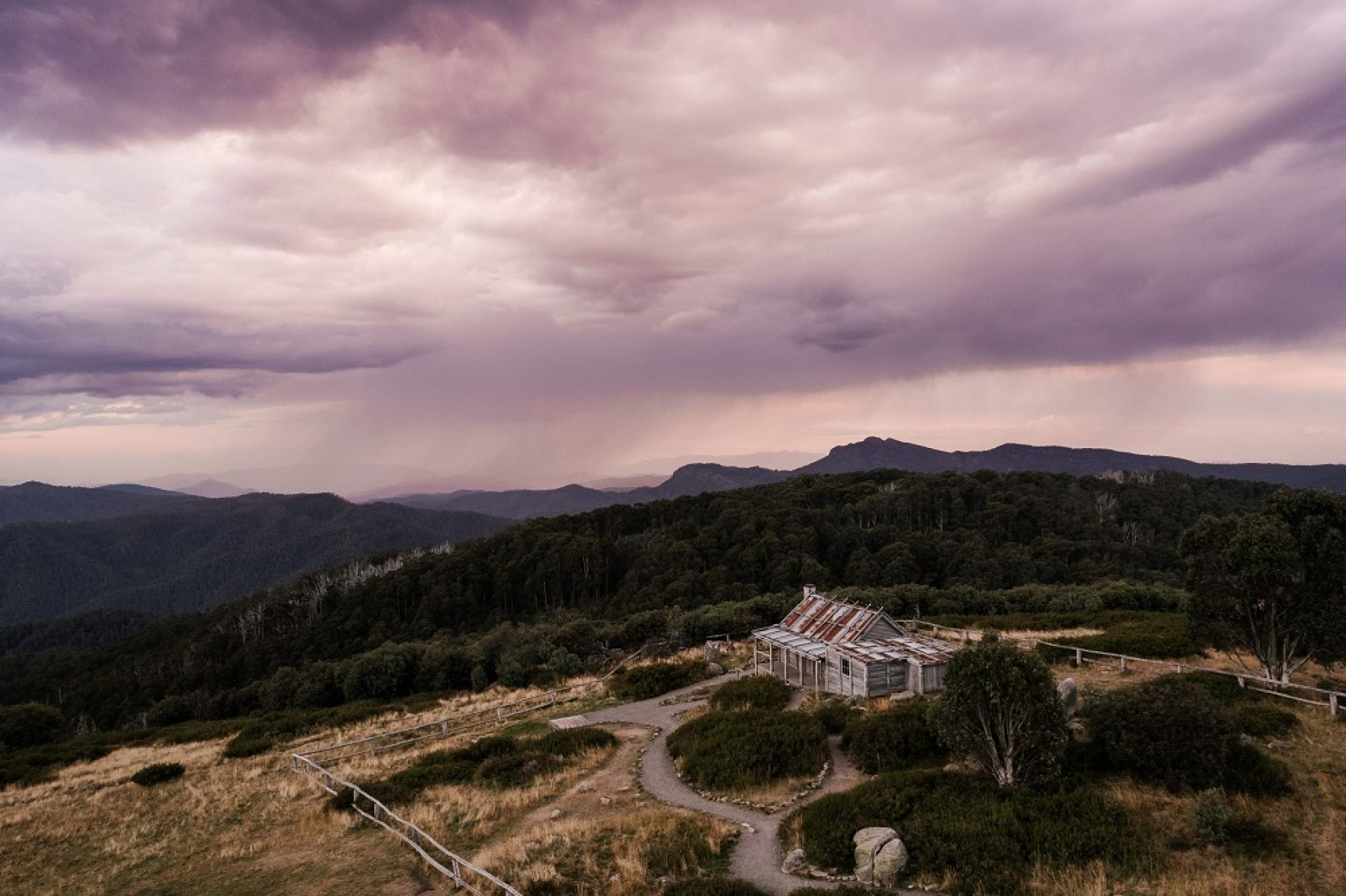 Mountain hut in grassy clearing surrounded by mountains