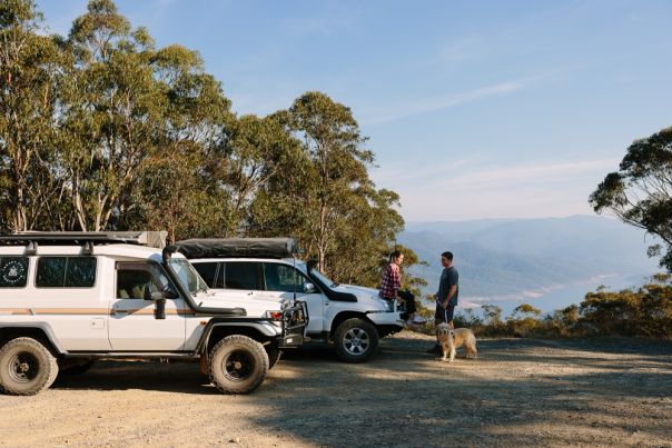 Two people with 4WD vehicles with Thomson Dam in background