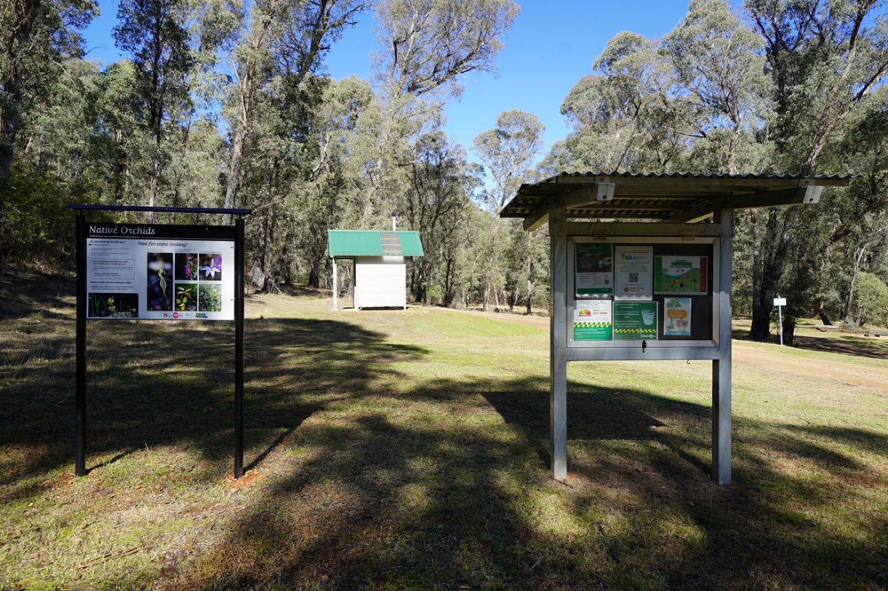 Signs and toilet in grassy clearing